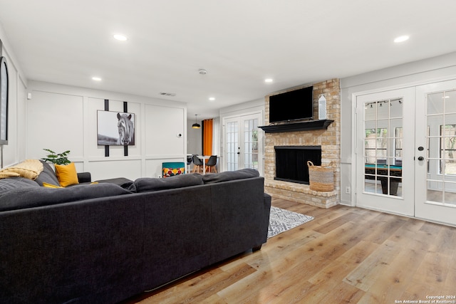 living room featuring a fireplace, light hardwood / wood-style flooring, and french doors