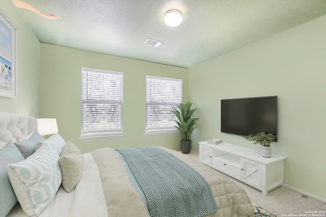 bedroom with light carpet and a textured ceiling