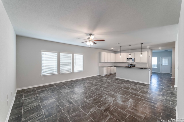 unfurnished living room featuring a textured ceiling and ceiling fan