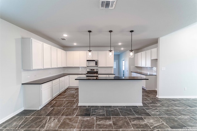 kitchen with white cabinets, hanging light fixtures, stainless steel appliances, a kitchen island, and decorative backsplash