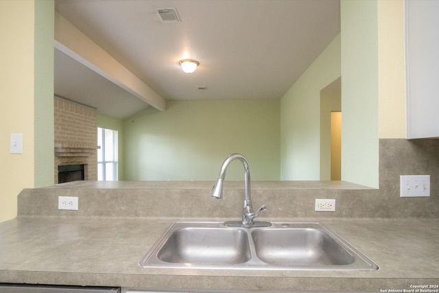 kitchen featuring a fireplace, sink, and vaulted ceiling with beams