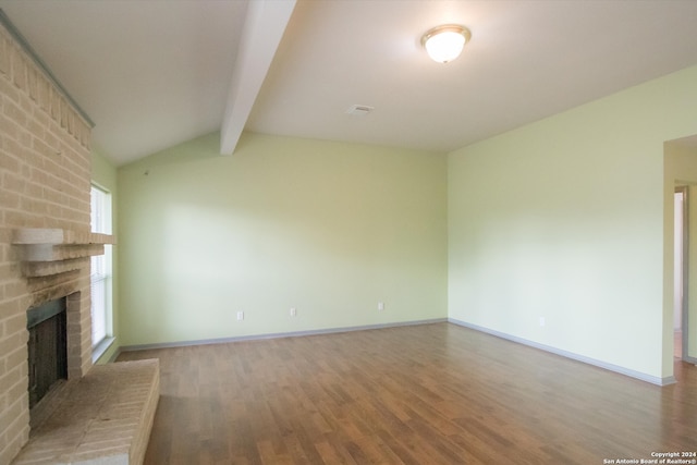 unfurnished living room with a fireplace, lofted ceiling with beams, and hardwood / wood-style flooring