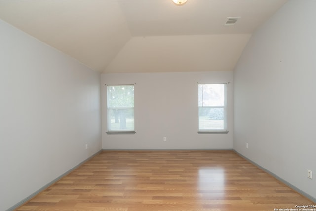 unfurnished room featuring vaulted ceiling and light hardwood / wood-style floors