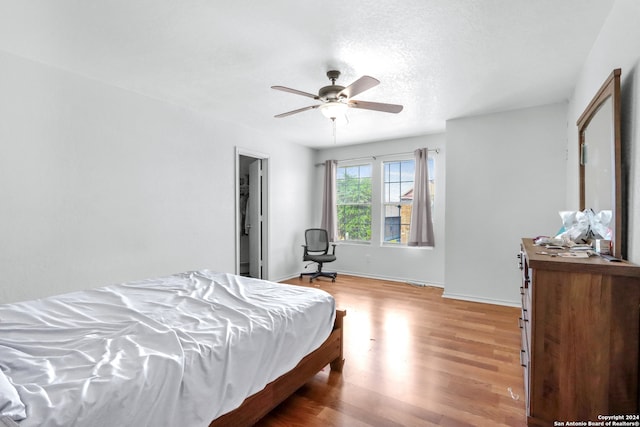 bedroom with ceiling fan, a textured ceiling, and light wood-type flooring