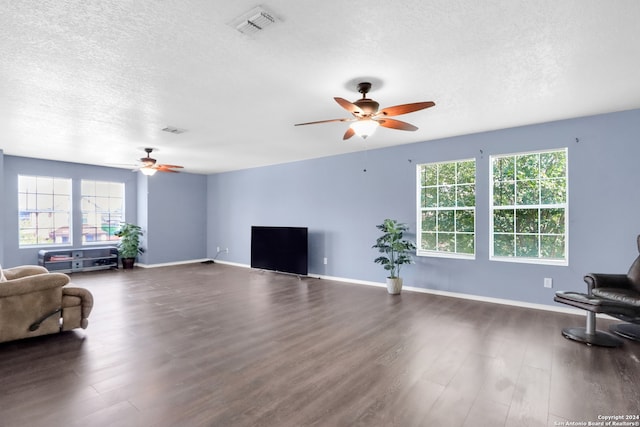 living room featuring a textured ceiling, dark wood-type flooring, ceiling fan, and plenty of natural light