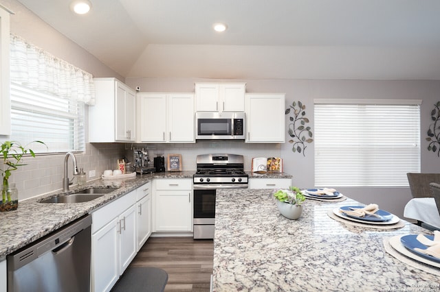 kitchen featuring stainless steel appliances, sink, vaulted ceiling, and white cabinets