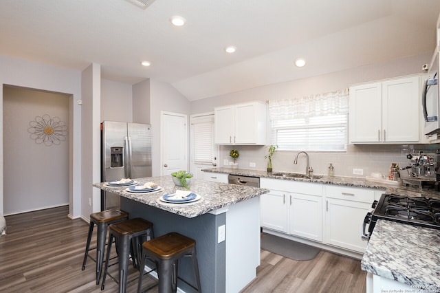 kitchen featuring white cabinets, a center island, light wood-type flooring, sink, and lofted ceiling