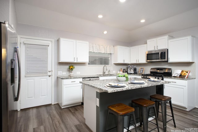 kitchen featuring dark wood-type flooring, stainless steel appliances, a sink, and a kitchen breakfast bar