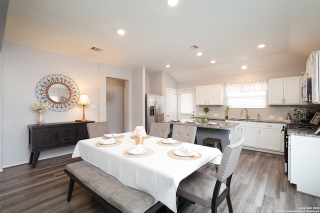 dining room featuring dark wood-type flooring, vaulted ceiling, and sink