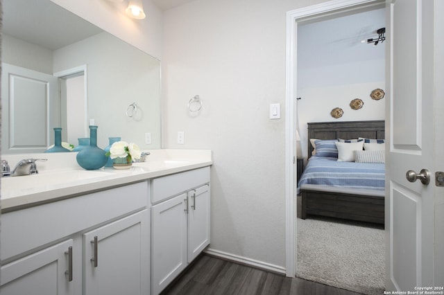 full bathroom with double vanity, ensuite bathroom, a sink, and wood finished floors