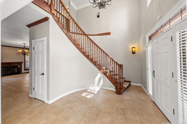 tiled foyer with a chandelier, crown molding, and a towering ceiling