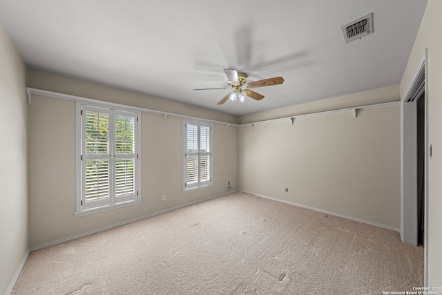 empty room with ceiling fan and light carpet