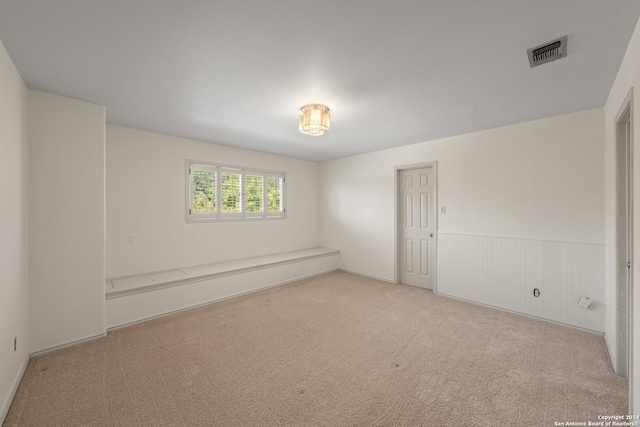 empty room featuring light carpet and wood walls