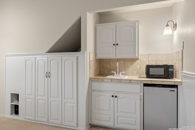 kitchen featuring stainless steel refrigerator, sink, tile countertops, and white cabinets