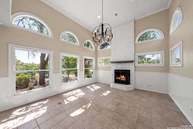 unfurnished living room with a notable chandelier, a fireplace, plenty of natural light, and crown molding