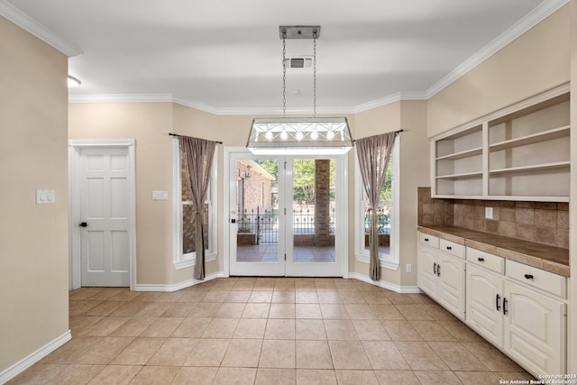 interior space featuring pendant lighting, french doors, ornamental molding, white cabinets, and light tile patterned flooring