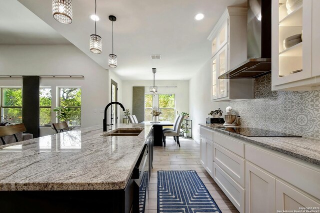 kitchen featuring a kitchen island with sink, sink, black electric cooktop, wall chimney range hood, and white cabinets