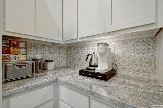 kitchen with tasteful backsplash, light stone countertops, and white cabinets