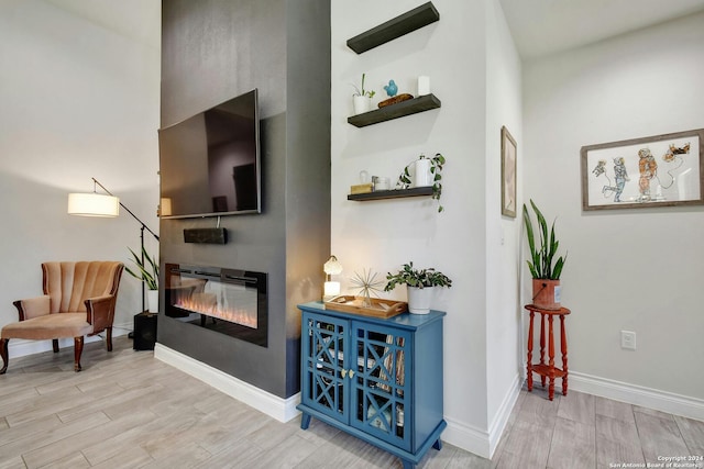 sitting room with baseboards, wood finished floors, and a glass covered fireplace