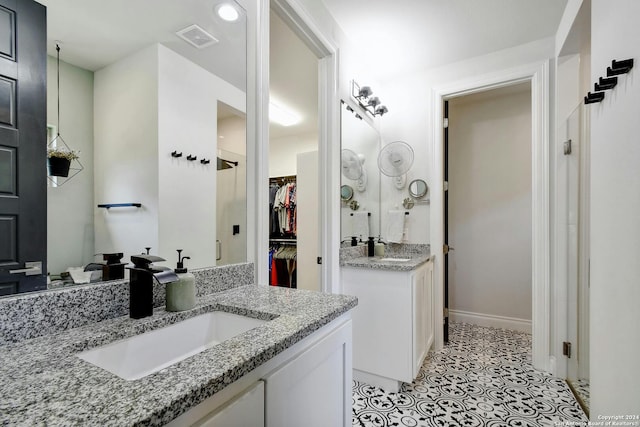 bathroom featuring two vanities, visible vents, a spacious closet, a sink, and tile patterned flooring