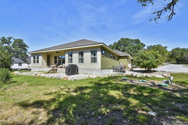 rear view of property featuring a ceiling fan and a lawn