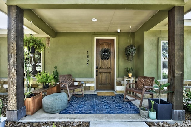 doorway to property featuring covered porch and stucco siding