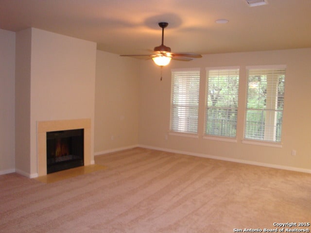 unfurnished living room featuring ceiling fan and carpet floors