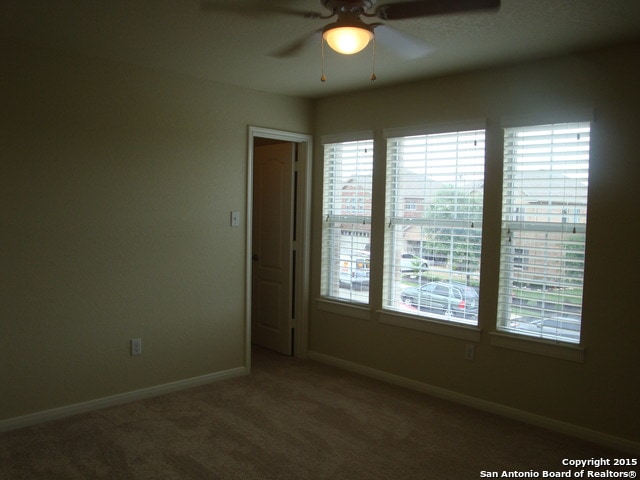 carpeted spare room with ceiling fan