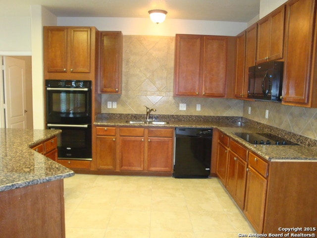 kitchen with black appliances, sink, dark stone counters, and tasteful backsplash