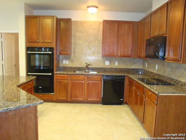 kitchen with tasteful backsplash, dark stone counters, a sink, and black appliances