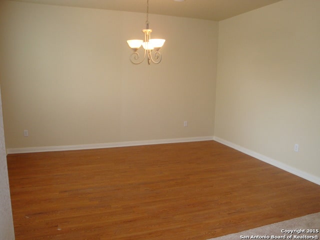 unfurnished room featuring hardwood / wood-style flooring and a notable chandelier