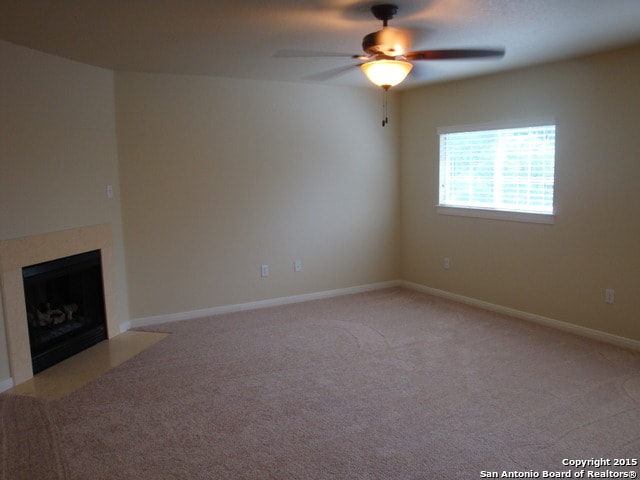 unfurnished living room featuring carpet flooring and ceiling fan