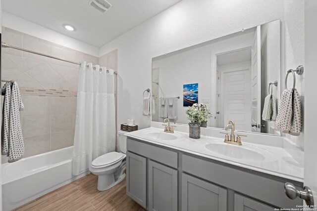 full bathroom with shower / bathtub combination with curtain, wood-type flooring, toilet, and vanity