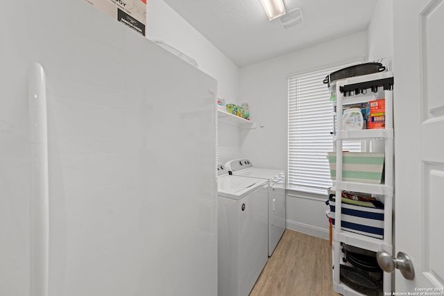 laundry room with plenty of natural light, washing machine and dryer, and light hardwood / wood-style flooring