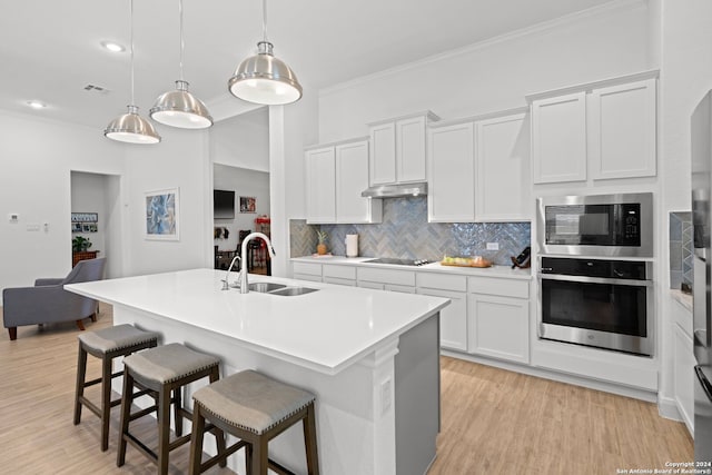 kitchen featuring white cabinetry, oven, sink, built in microwave, and a center island with sink