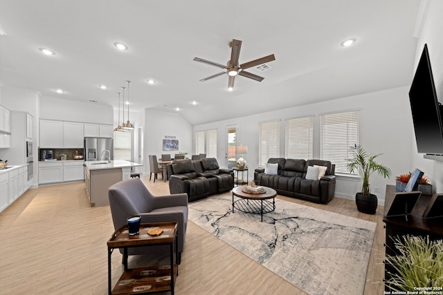 living room featuring light wood-type flooring, lofted ceiling, sink, and ceiling fan