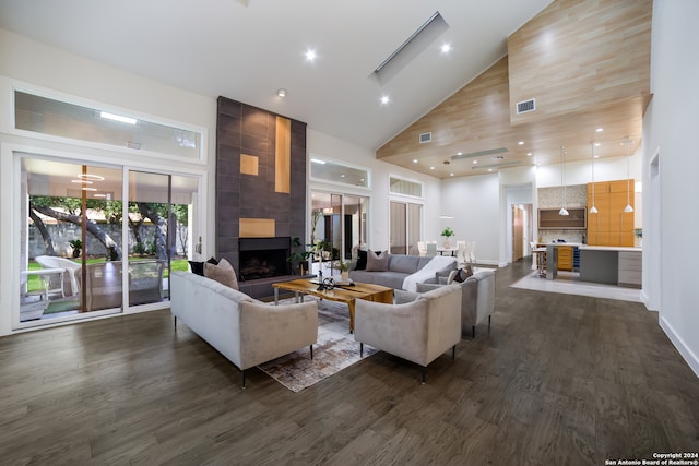 living room with high vaulted ceiling, a tiled fireplace, and dark hardwood / wood-style floors