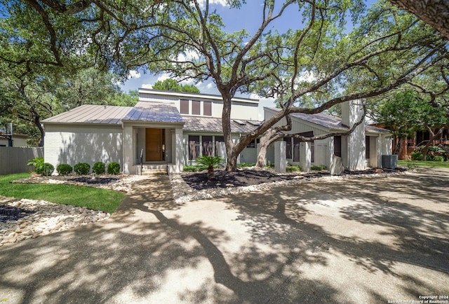 mid-century inspired home with metal roof, brick siding, and fence