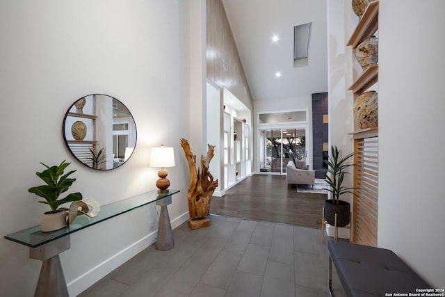 entrance foyer featuring baseboards, a towering ceiling, and wood finished floors