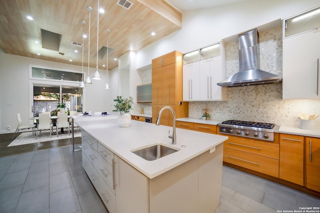 kitchen with a sink, stainless steel gas cooktop, decorative backsplash, and wall chimney range hood