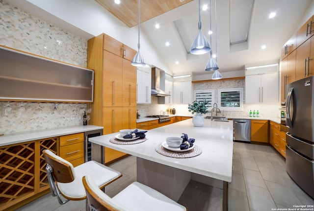 kitchen featuring tasteful backsplash, wine cooler, stainless steel appliances, wall chimney exhaust hood, and a kitchen island with sink