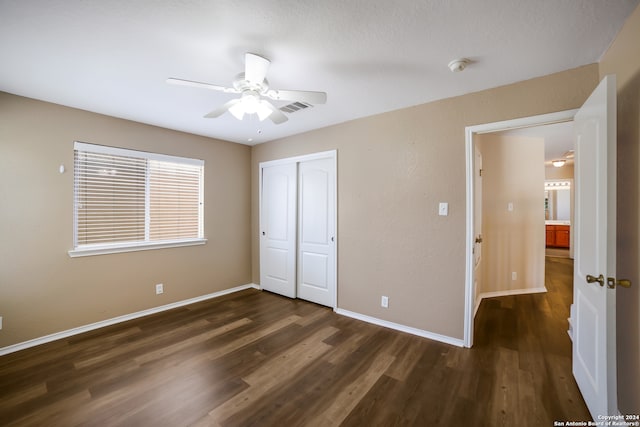 unfurnished bedroom featuring dark wood-type flooring, a closet, and ceiling fan