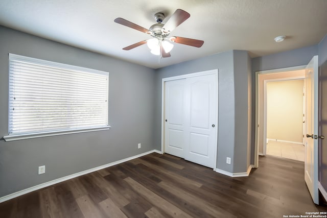 unfurnished bedroom featuring a closet, a textured ceiling, ceiling fan, and dark hardwood / wood-style flooring