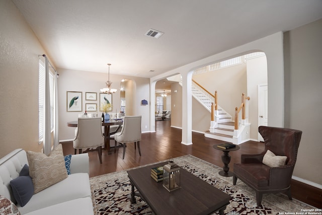 living room with ceiling fan with notable chandelier and dark hardwood / wood-style flooring