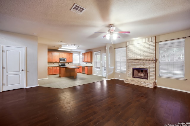 unfurnished living room featuring light hardwood / wood-style flooring, a textured ceiling, and ceiling fan