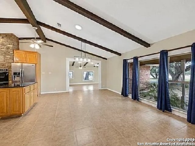 unfurnished living room with vaulted ceiling with beams, ceiling fan with notable chandelier, and a healthy amount of sunlight