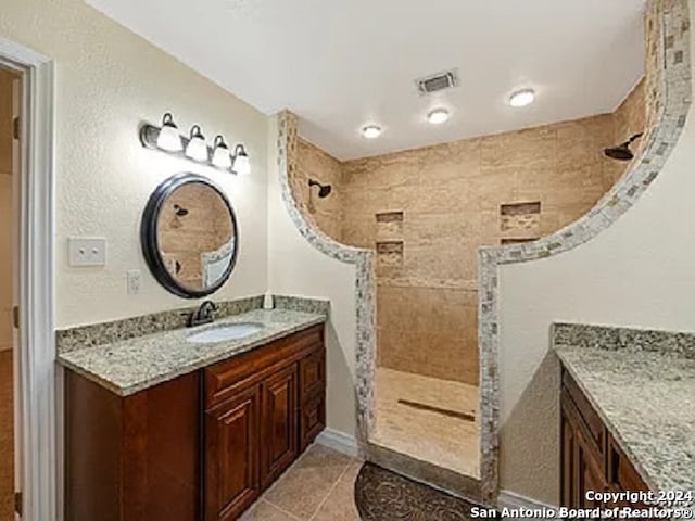 bathroom featuring a tile shower, tile patterned floors, and vanity