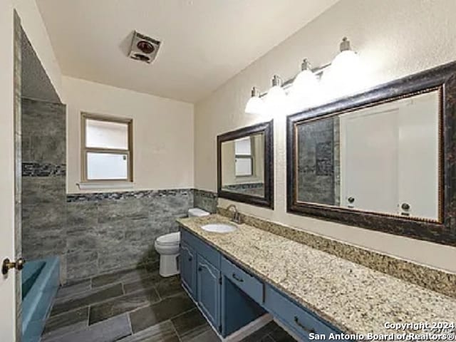 bathroom featuring tile walls, vanity, and toilet