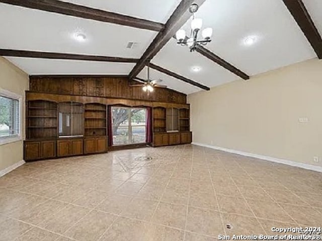 unfurnished living room with ceiling fan with notable chandelier, lofted ceiling with beams, light tile patterned floors, and a healthy amount of sunlight