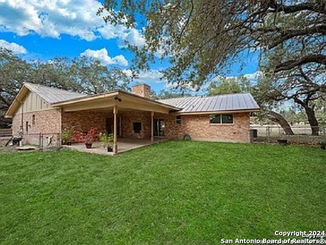 rear view of house featuring a lawn and a patio area